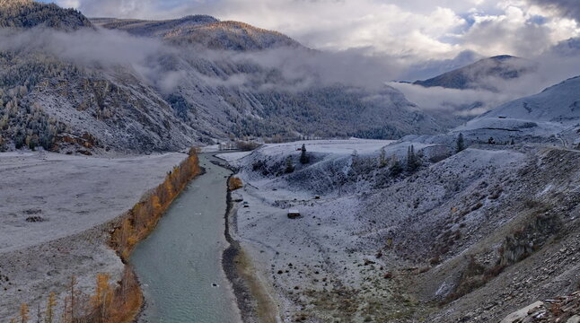 Russia. Western Siberia, Altai Mountains. Stunning contrasts of the first snow on mountain cliffs and yellow larches in the Chuya River valley along the Chuya highway.
