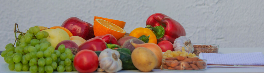 Blank notepad for writing a diet plan against a background of fruits, vegetables, and grains