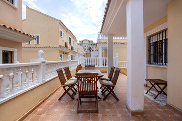 Charming outdoor dining area on tiled terrace with wooden chairs and white balustrade architecture