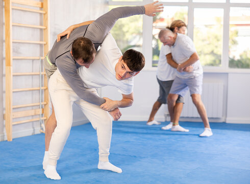 Adult man and young guy training judo techniques in studio..