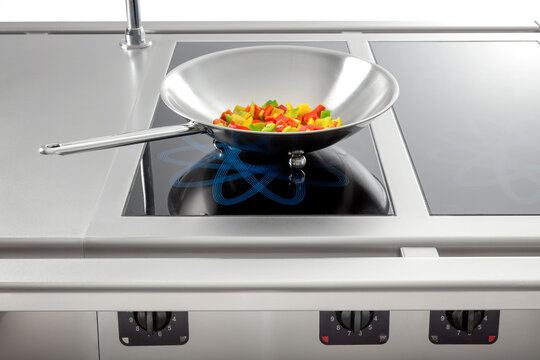 Stainless induction cooktop with wok containing red, yellow, and green bell peppers—clean and modern.