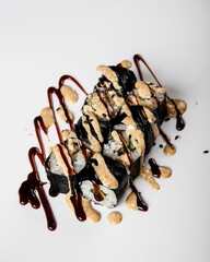 Modern presentation of noriwrapped maki with glossy sauce and toppings