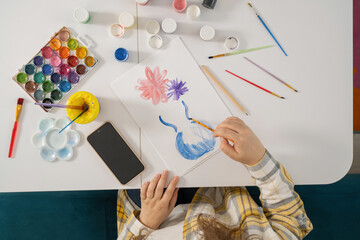 Woman painting colorful flowers with watercolors, artistic hobby.