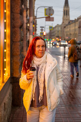 Obraz premium A Caucasian woman walks alone through a metropolis during the rain, tourism