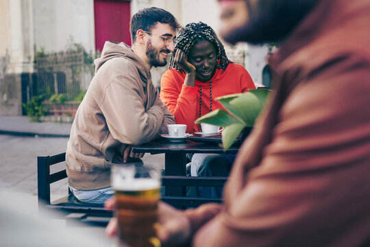 Friends chatting at outdoor cafe, diverse group drinking coffee and socializing in city