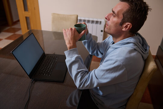 Remote Worker Man At Home Office Enjoying Coffee While Working On Laptop