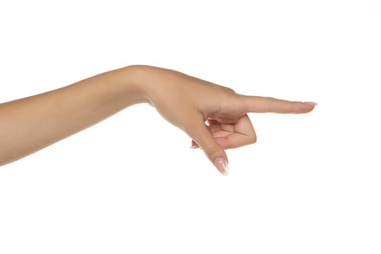 Studio close-up of female hand with natural manicure pointing with index finger to the side on white background.