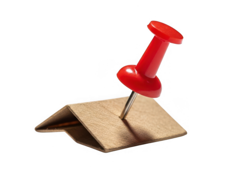 Red thumbtack pushpin securing a folded brown kraft paper note, isolated on white background