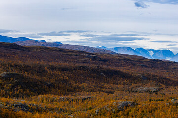Autumn landscape of Kilpisjarvi, Finland, showcasing colorful foliage, serene lakes, and majestic mountains in the background.