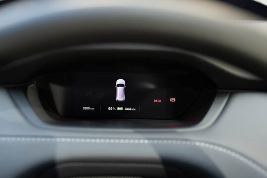 Electric car dashboard view when parked at power charging station. Zero emission car. Long range electric vehicle. Future of cars. Many different car dashboard lights with warning lamps illuminated.