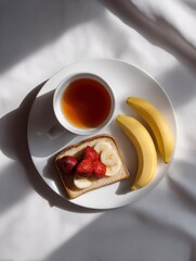 White plate with a slice of toast on it. the toast is topped with sliced bananas and fresh strawberries. next to the toast, there are two bananas. on the plate, there is also a small cup of tea.