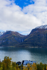 Autumn landscape in Lustrafjorden, South Norway, featuring clear water reflections, mountains, and colorful foliage.
