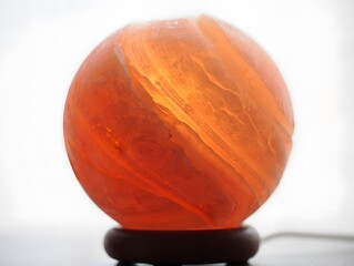 Glowing orange sphere shaped himalayan salt lamp on wooden base