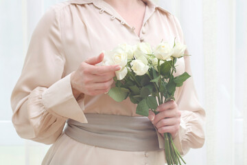 Woman holds a bouquet of white roses, copy space.