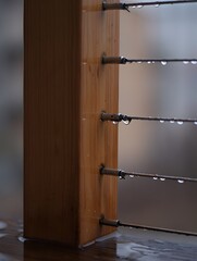 Raindrops clinging to modern cable railing on a wooden post