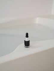 Small black dropper bottle with clear cap on a textured surface