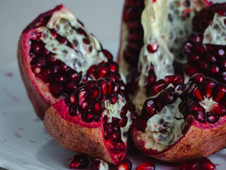 fresh ripe pomegranate on white plate with seeds. pomegranate cutting