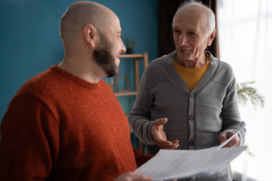Accounting, finance or refund, mortgage and tax. Senior father with adult son in home reading documents for bank payment.