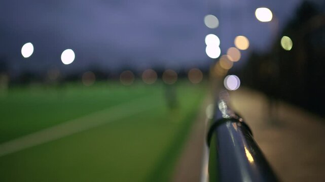 Night view of a football training session on an artificial turf field under bright floodlights with small goals and cones set up for youth practice