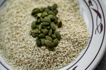 Pumpkin seeds without shells on top of sesame seeds — close-up