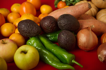 Fresh Produce Assortment With Avocados, Peppers, Apples And Onions On Red Background