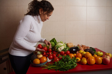 Woman Arranging Fresh Vegetables and Fruits on Red Table for Healthy Grocery Spread