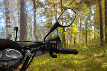 Fototapeta premium right handlebar, throttle handle, ATV windshield, steering wheel and rear view mirrors. Quad bike or ATV stands idle among tall trees and lush greenery