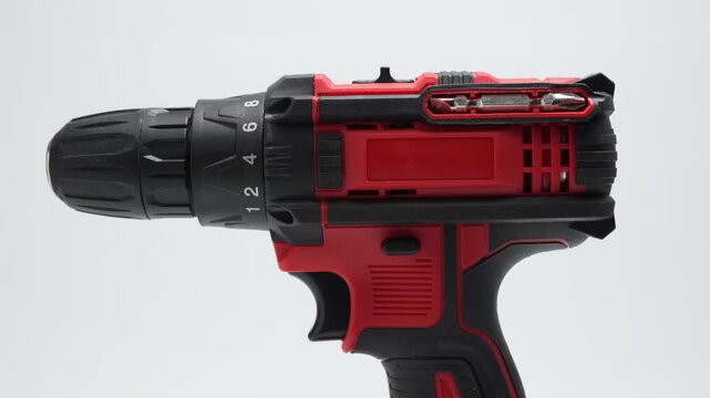 Red cordless drill driver rotates on a white background. Close-up shows the chuck and torque ring in clean studio light.