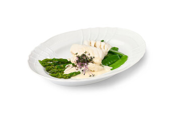 White fish fillet, asparagus, and snow peas served with a creamy sauce on a white plate