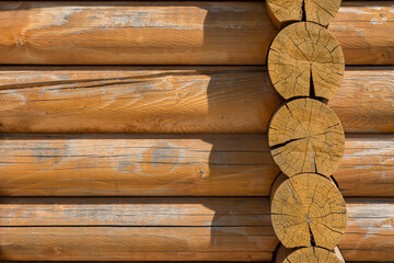 Background of a wall of logs illuminated by the sun
