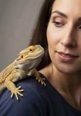 Woman with lizard perched on her shoulder and smiling at the camera  
