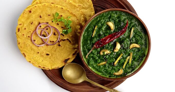 Makki Ki Roti & Sarson Ka Sag is basically Corn floor flat bread & curry using mustard greens respectively. Popular Punjabi food. Served in a bowl and plate over moody background. selective focus