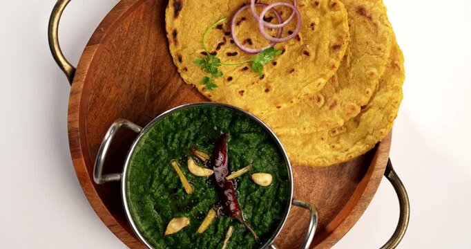 Makki Ki Roti & Sarson Ka Sag is basically Corn floor flat bread & curry using mustard greens respectively. Popular Punjabi food. Served in a bowl and plate over moody background. selective focus
