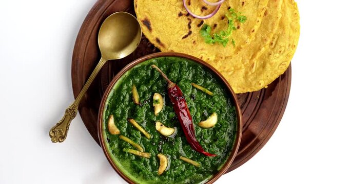 Makki Ki Roti & Sarson Ka Sag is basically Corn floor flat bread & curry using mustard greens respectively. Popular Punjabi food. Served in a bowl and plate over moody background. selective focus