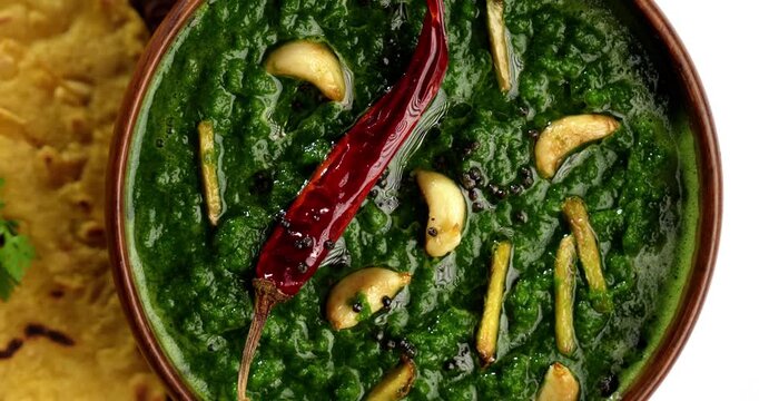 Makki Ki Roti & Sarson Ka Sag is basically Corn floor flat bread & curry using mustard greens respectively. Popular Punjabi food. Served in a bowl and plate over moody background. selective focus