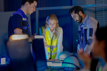 A female technician in a safety vest uses a radio for incident response in a smart factory. She is monitoring an AI-driven automation system in a command center.