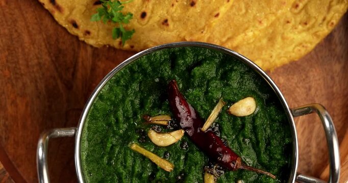 Makki Ki Roti & Sarson Ka Sag is basically Corn floor flat bread & curry using mustard greens respectively. Popular Punjabi food. Served in a bowl and plate over moody background. selective focus