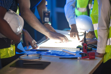 A close up of engineers reviewing a CAD blueprint on a light table. The team is in a smart factory...