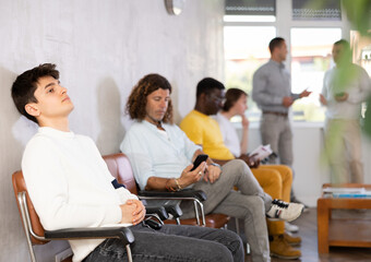 Portrait of a young man sitting in a chair in the lobby waiting
