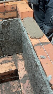 Building a heating stove, Bricklayer laying brickwork, The stove core is lined with mineral wool, Vertical video