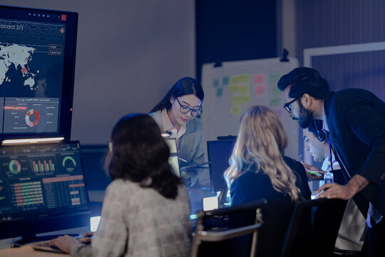 Dynamic night ops hub action Diverse team collaborates intensely analyzing critical data screens leader provides guidance modern command center buzz achieves mission goals now teamwork boost.