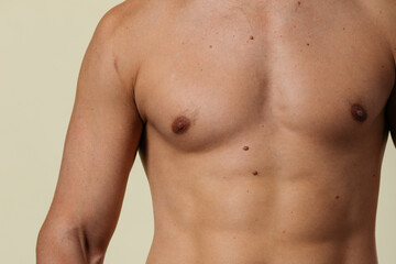 Fototapeta premium A close-up of a slender young man's torso. Male body parts: defined abs and toned chest. Scene: a doctor's appointment in an X-ray room. moles and birthmarks on the body