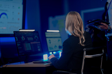 Command center lead focused intense monitoring critical systems late night headset connects team analyzing real time data screen crucial vigilance protects infrastructure operation underway now execut