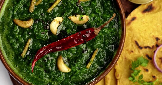 Makki Ki Roti & Sarson Ka Sag is basically Corn floor flat bread & curry using mustard greens respectively. Popular Punjabi food. Served in a bowl and plate over moody background. selective focus
