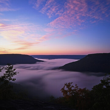 Breathtaking sunrise over misty valley with rolling clouds and colorful sky
