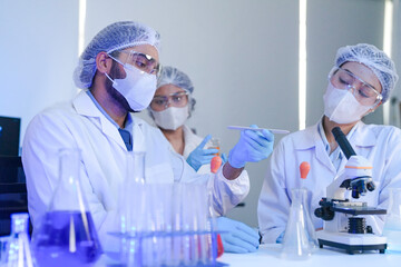 Diverse team of scientists in protective gear collaborating in modern blue lab, analyzing DNA helix...