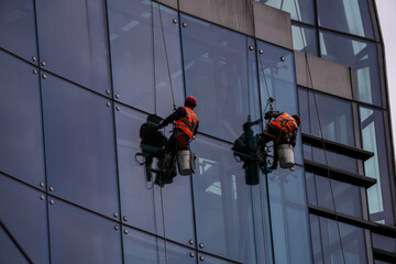 workers suspended on harnesses clean glass windows