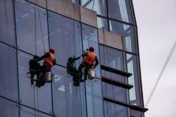 workers suspended on harnesses clean glass windows © ultramansk