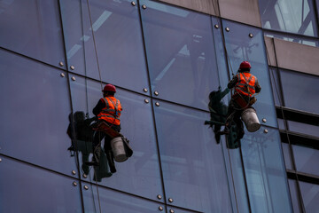 workers suspended on harnesses clean glass windows