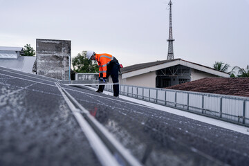 Engineer installing solar panels on wet metal rooftop during cloudy weather